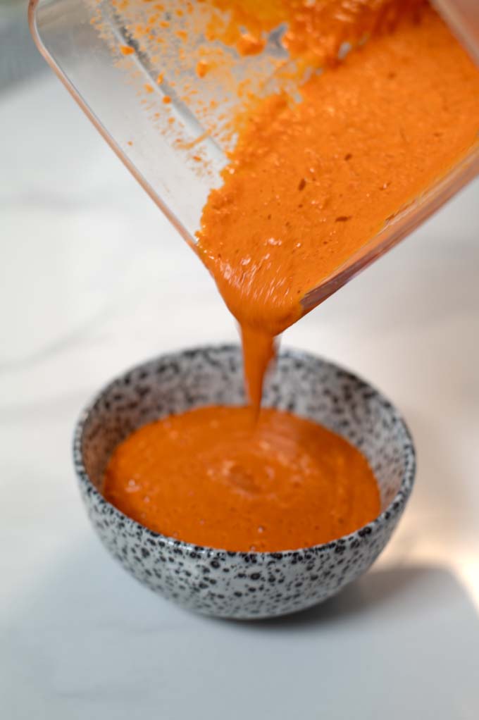 Salsa Crema is poured from the bowl of a blender into a small serving bowl.