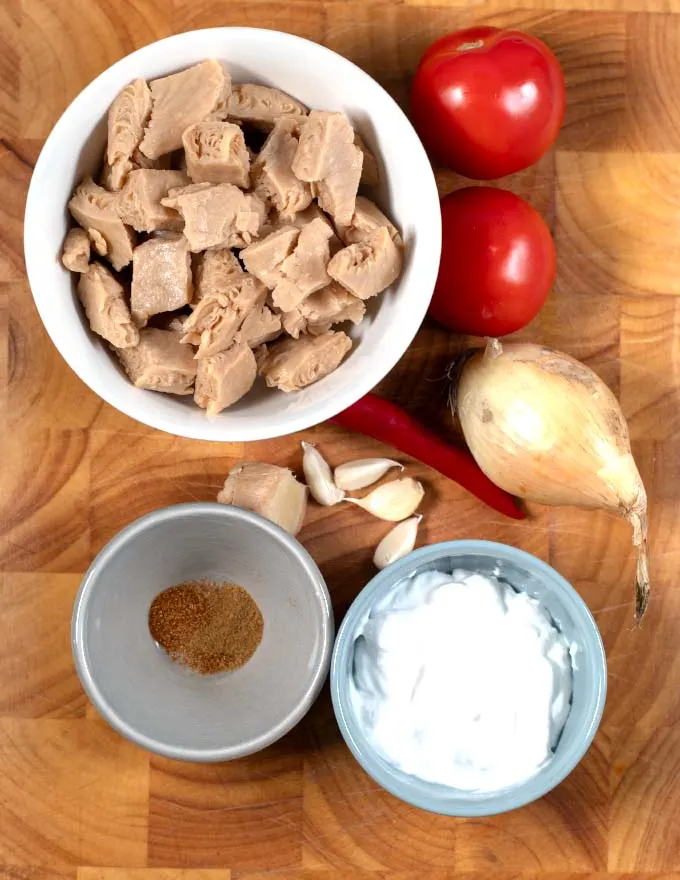 Ingredients needed to make Chicken Pakistani collected on a board.