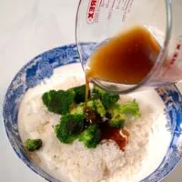 Thai Brown Sauce is poured over a serving of white rice with broccoli.