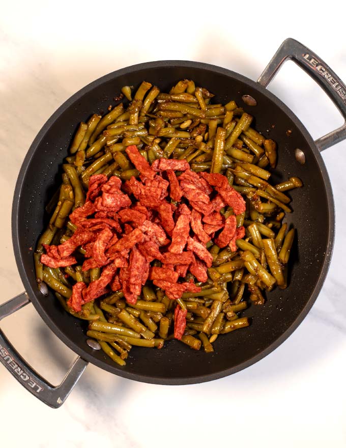 Vegan bacon is mixed with the green beans.