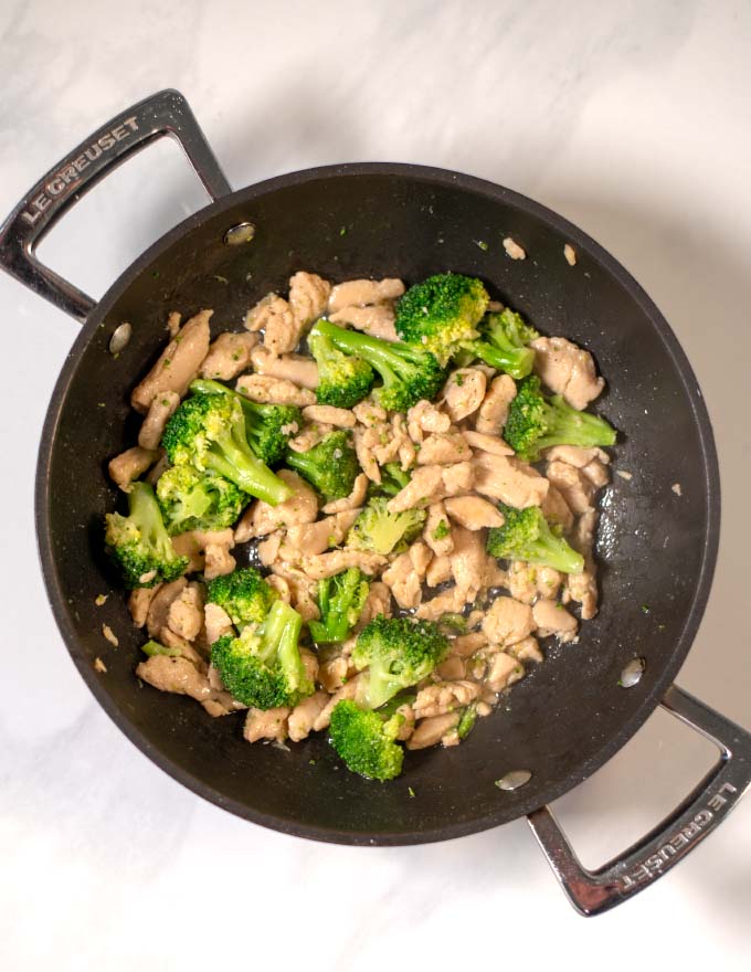 Vegan chicken and broccoli florets are sautéed in a pan.