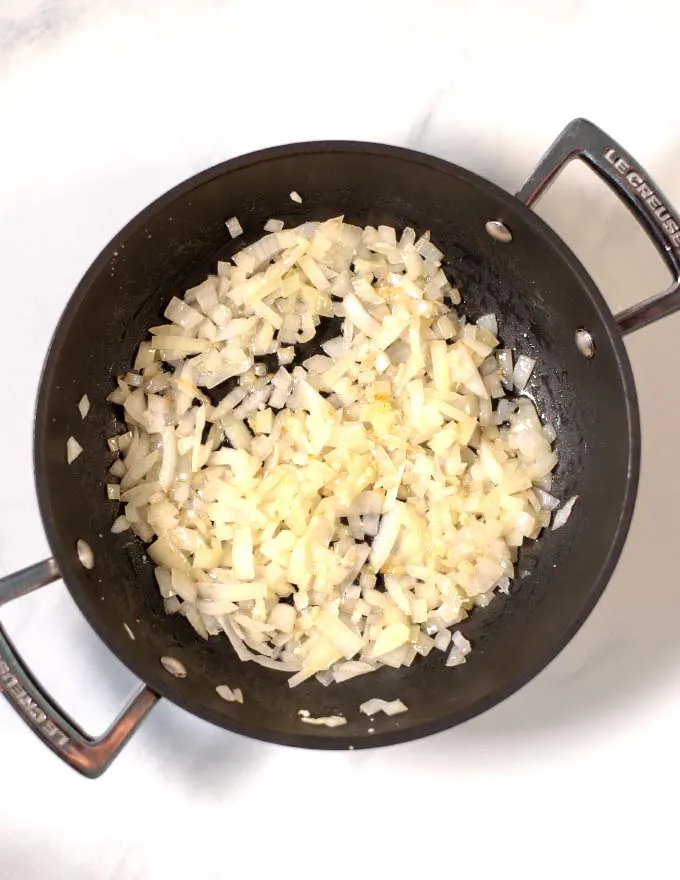 Step of frying diced onions with garlic in oil.