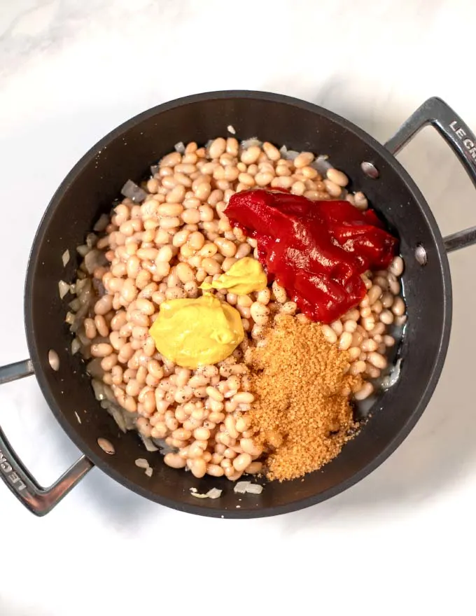 White beans, tomato paste, ketchup, and seasonings are given into a pan.