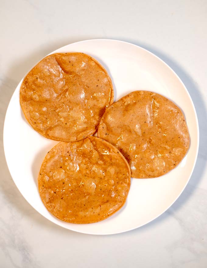 View of three fried tortillas on a white plate.