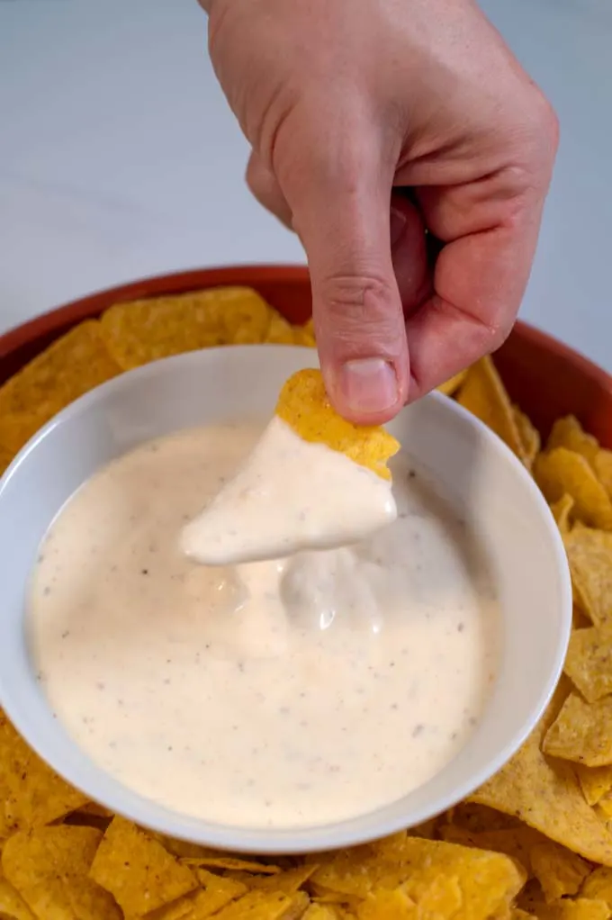 A tortilla chip is dipped into sauce.