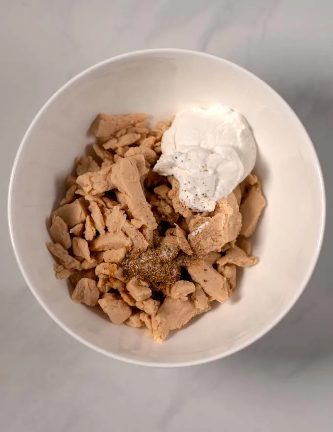 Top view of a mixing bowl with vegan chicken and marinade ingredients.