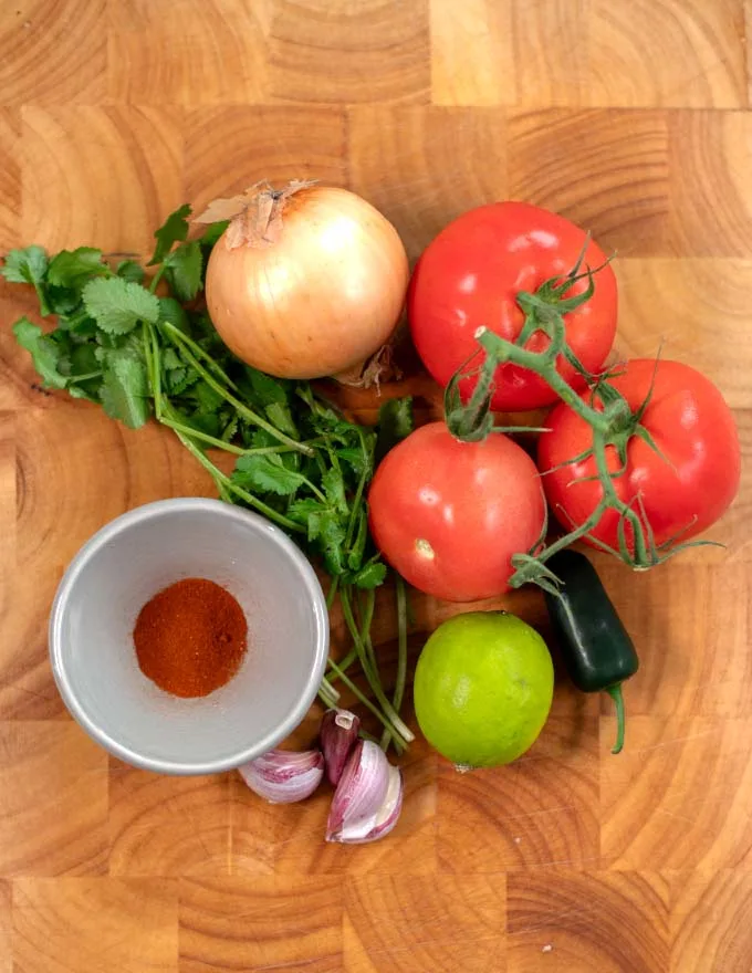 Ingredients needed to make Salsa Roja on a board.