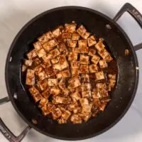 A frying pan with tofu cubes.