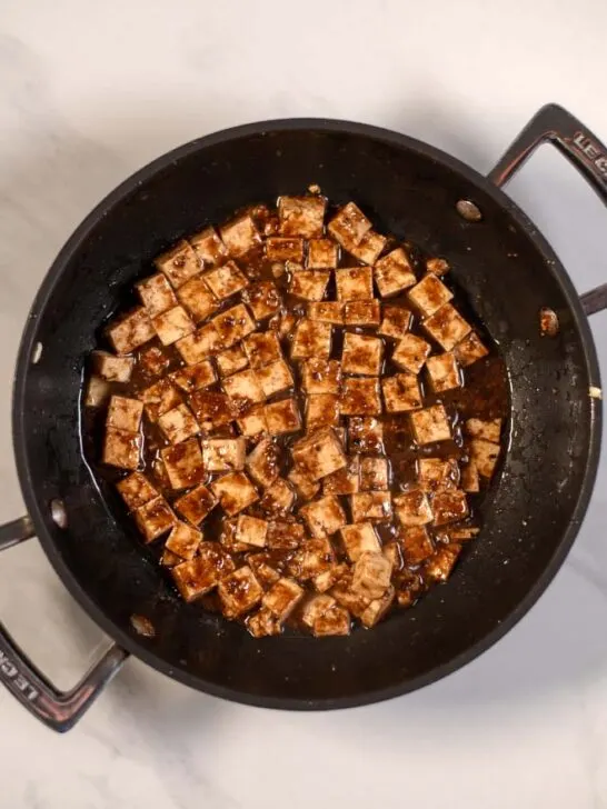 A frying pan with tofu cubes.