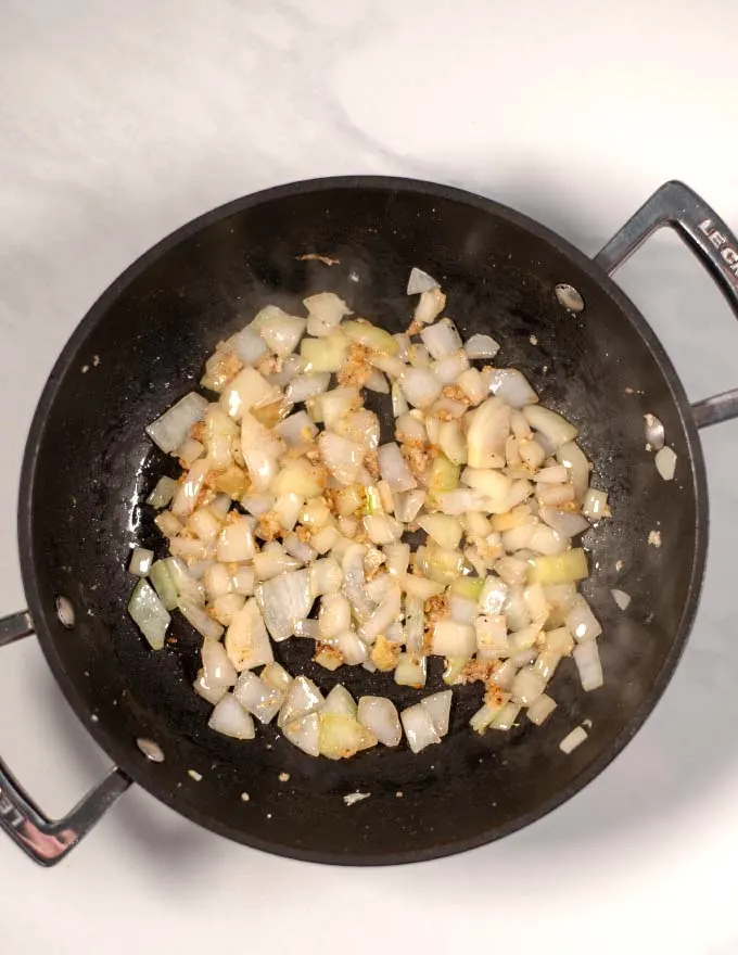 Onions, ginger, and garlic are fried in a pan.