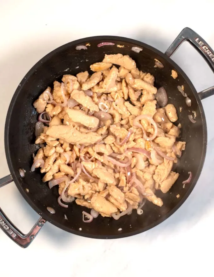 Shallots and vegan chicken is fried in a pan.