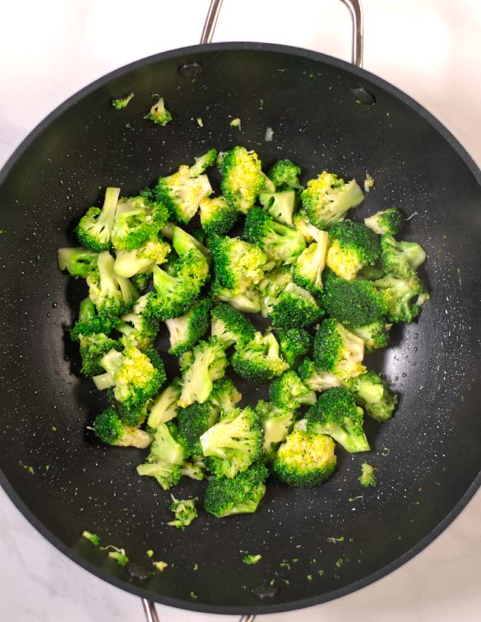 Broccoli florets are sautéed in a pan.