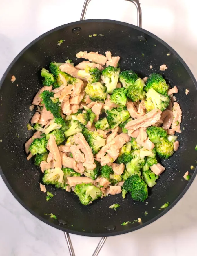 Chicken is fried with broccoli in a pan.