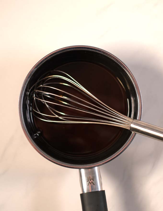 Mixed ingredients for Eel Sauce and a wire whisk.