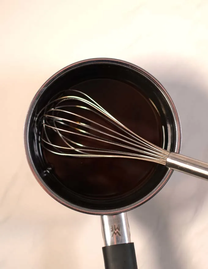 Mixed ingredients for Eel Sauce and a wire whisk.