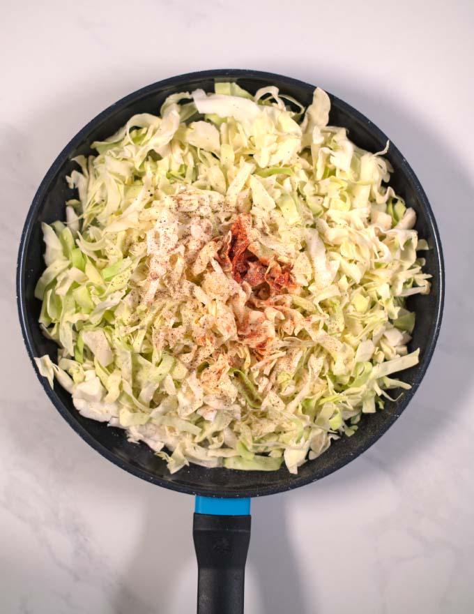 Shredded cabbage and seasonings added to the pan.