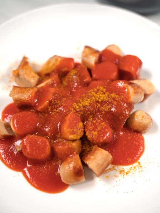 Closeup of a serving of sausages with Currywurst sauce.