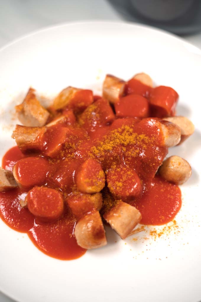 Closeup of a serving of sausages with Currywurst sauce.