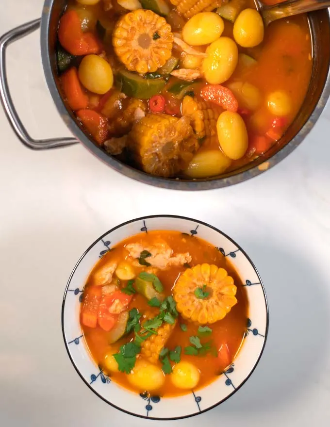 A serving of Caldo de Pollo with the cooking pot in the background.