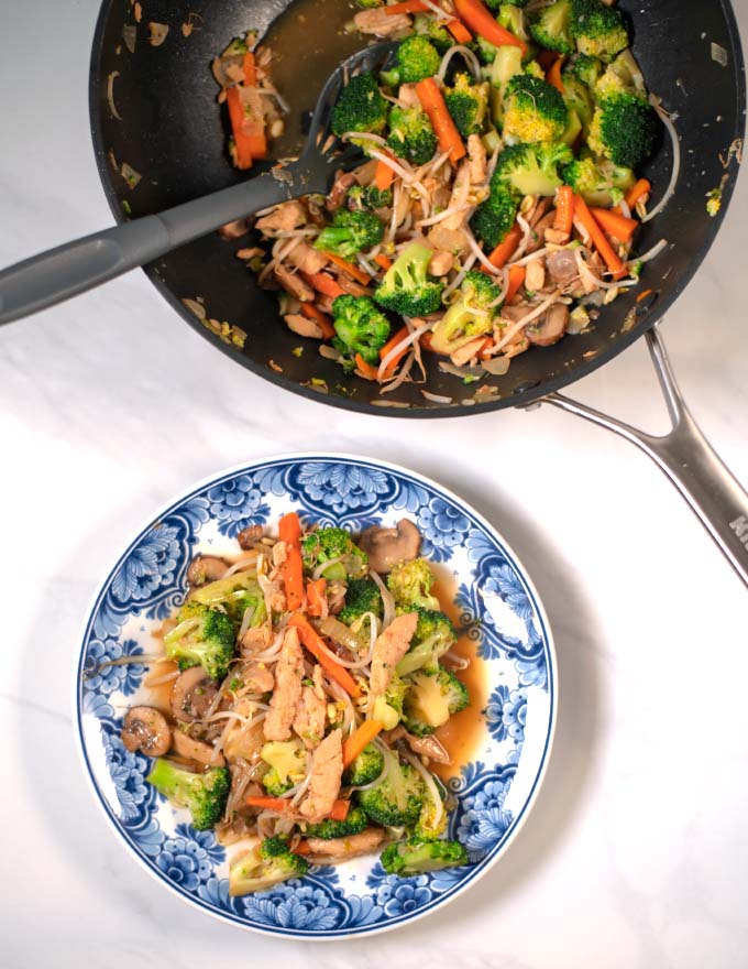 Serving of Chop Suey on a plate with wok in the background.