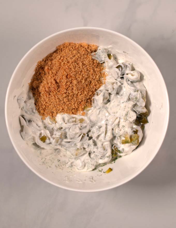 Part of the breadcrumbs and butter are given to the mixing bowl with the other ingredients of Fried Pickle Dip.