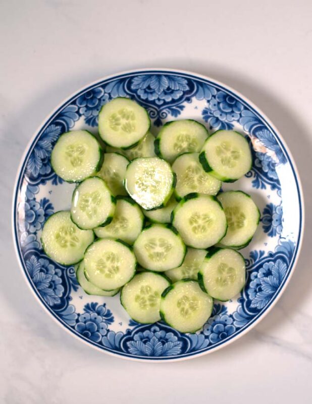 Cucumbers are sliced and given onto a plate.