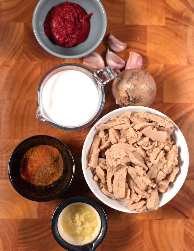 Ingredients needed to make the Best Indian Curry collected on a wooden board.