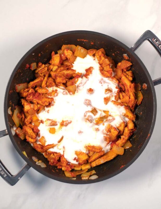 Coconut milk is given to the pan with the fried curried chicken.