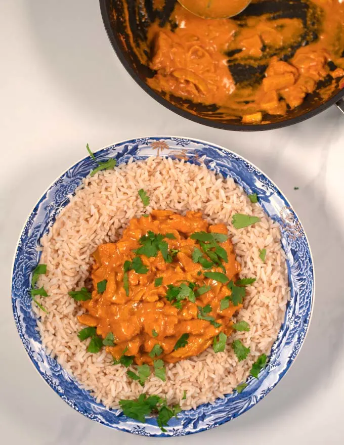 A serving of the best Indian Curry with rice and the pan in the background.