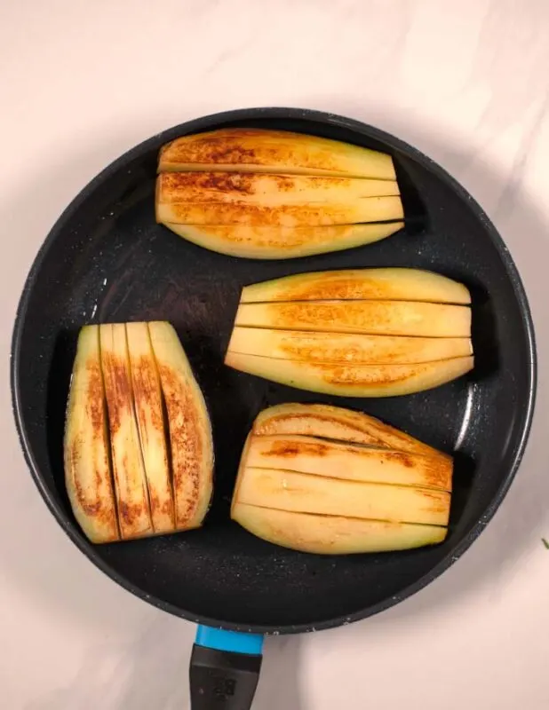 Eggplant halves are pre-fried in olive oil until brown.