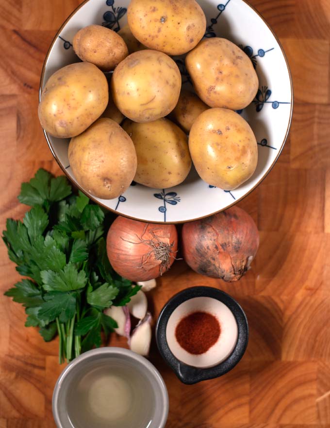 Ingredients needed to make Potatoes and Onions collected on a board.