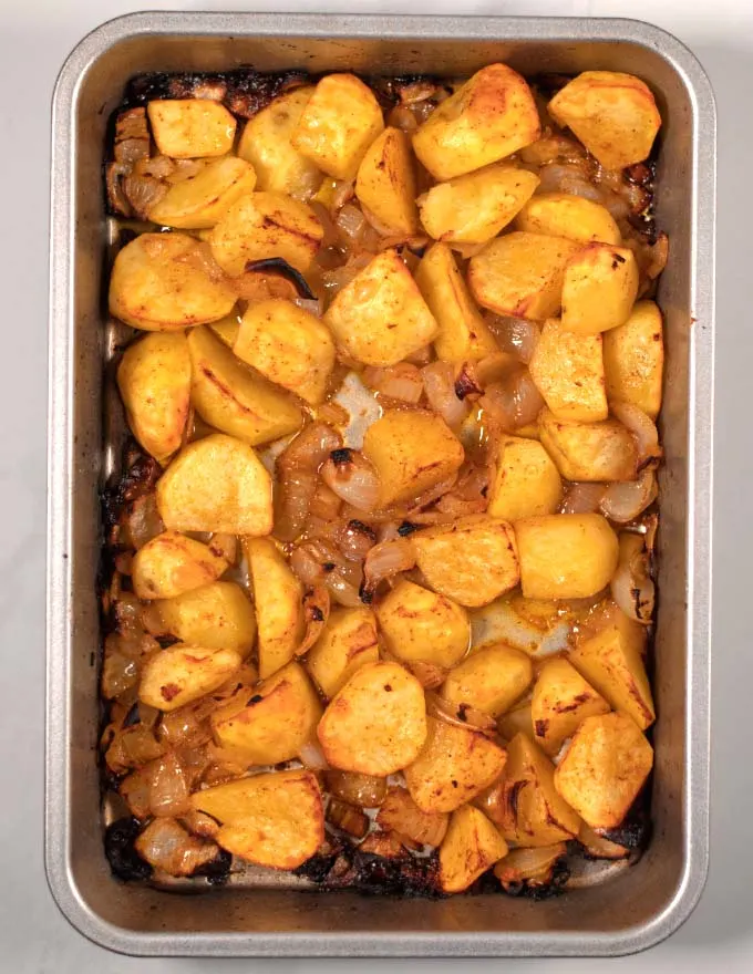 Oven-roasted potatoes and onions as they are coming out of the oven.