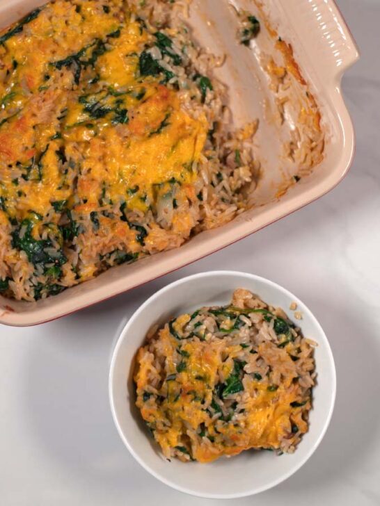 A serving of Spinach Rice Casserole in a bowl with the casserole dish in the background.