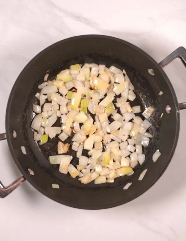 Onions and garlic are sauteed in a pan.