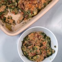 A serving of Chicken Artichoke Casserole with baking dish in the background.